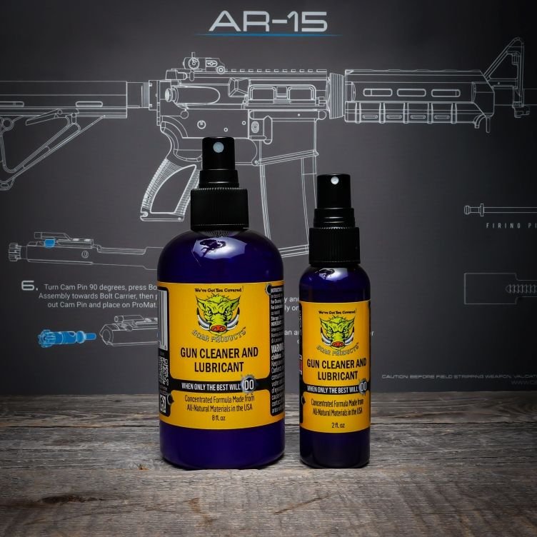 Photo of two bottle of Boar Products gun cleaner and lubricant in front of an AR-15 rifle cleaning mat