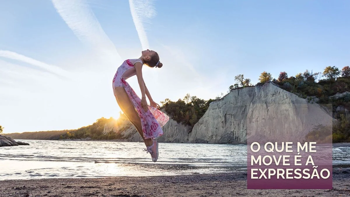young female dancer soars into the air on beach with clouds and sunshine shining on her