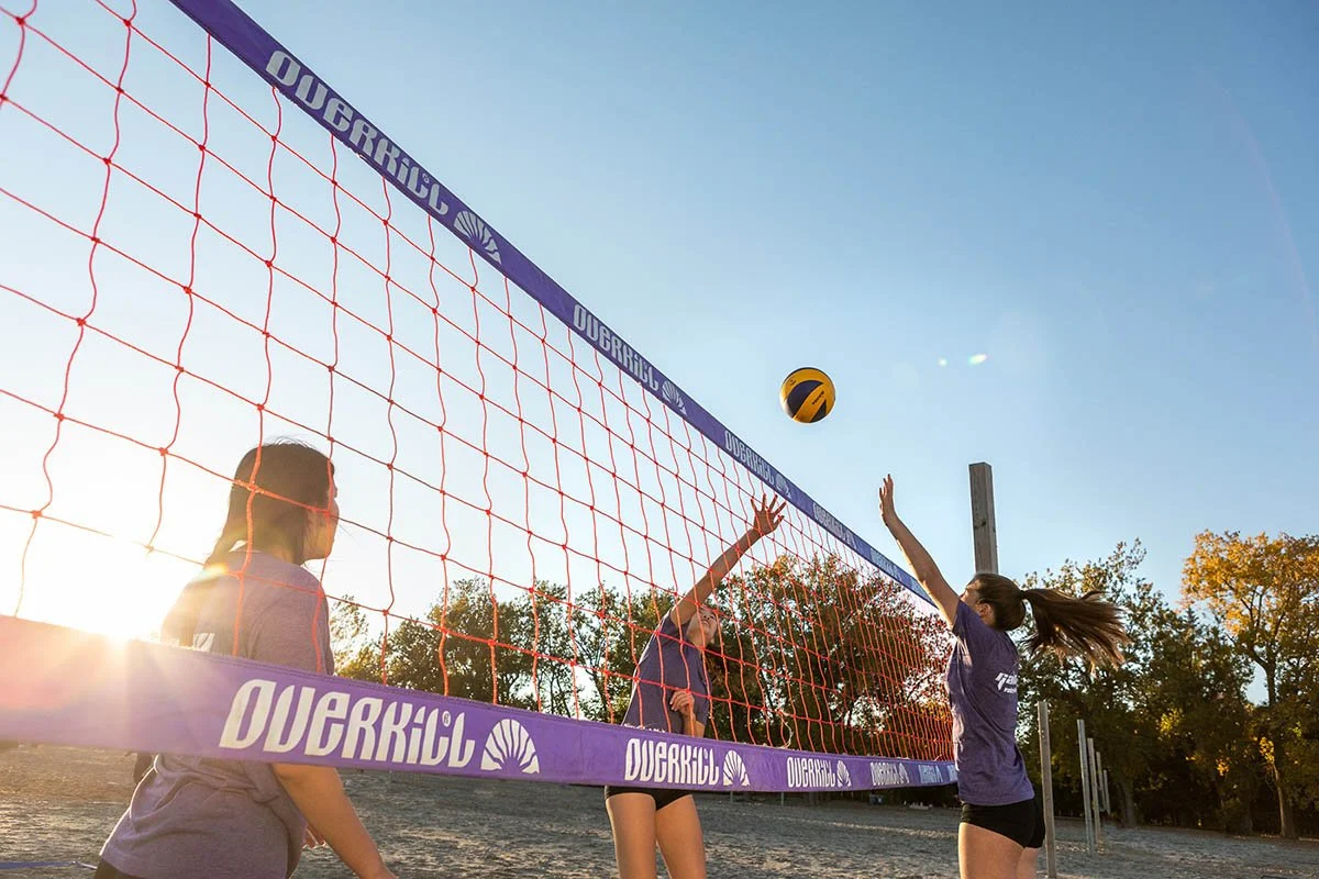 young girls play beach volleyball on beach with net