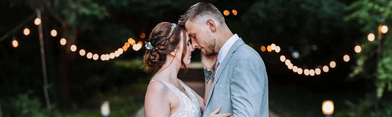 Bride and Groom embracing in front of fairy lights