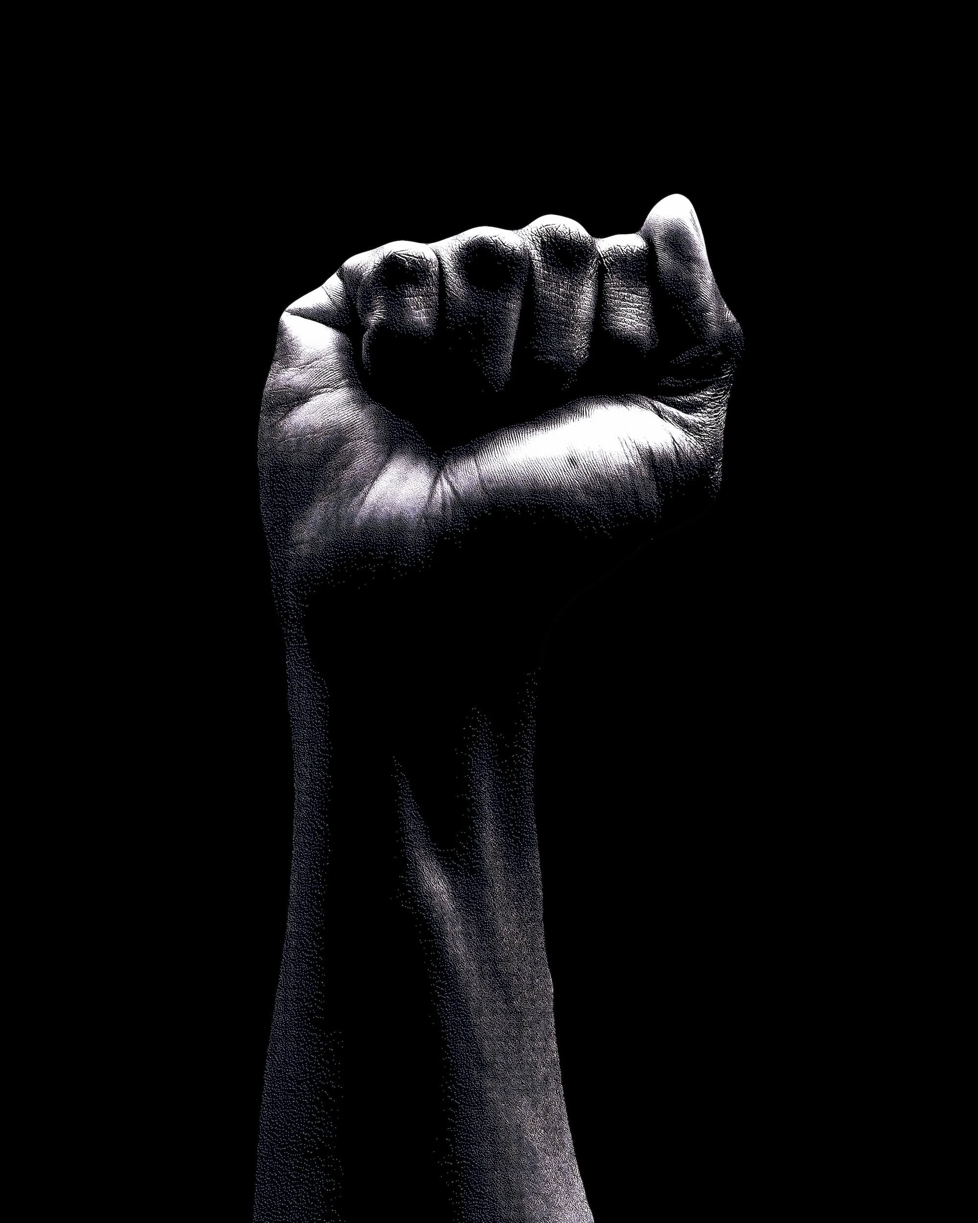Black and white raised fist on black background, symbolizing solidarity and resistance.