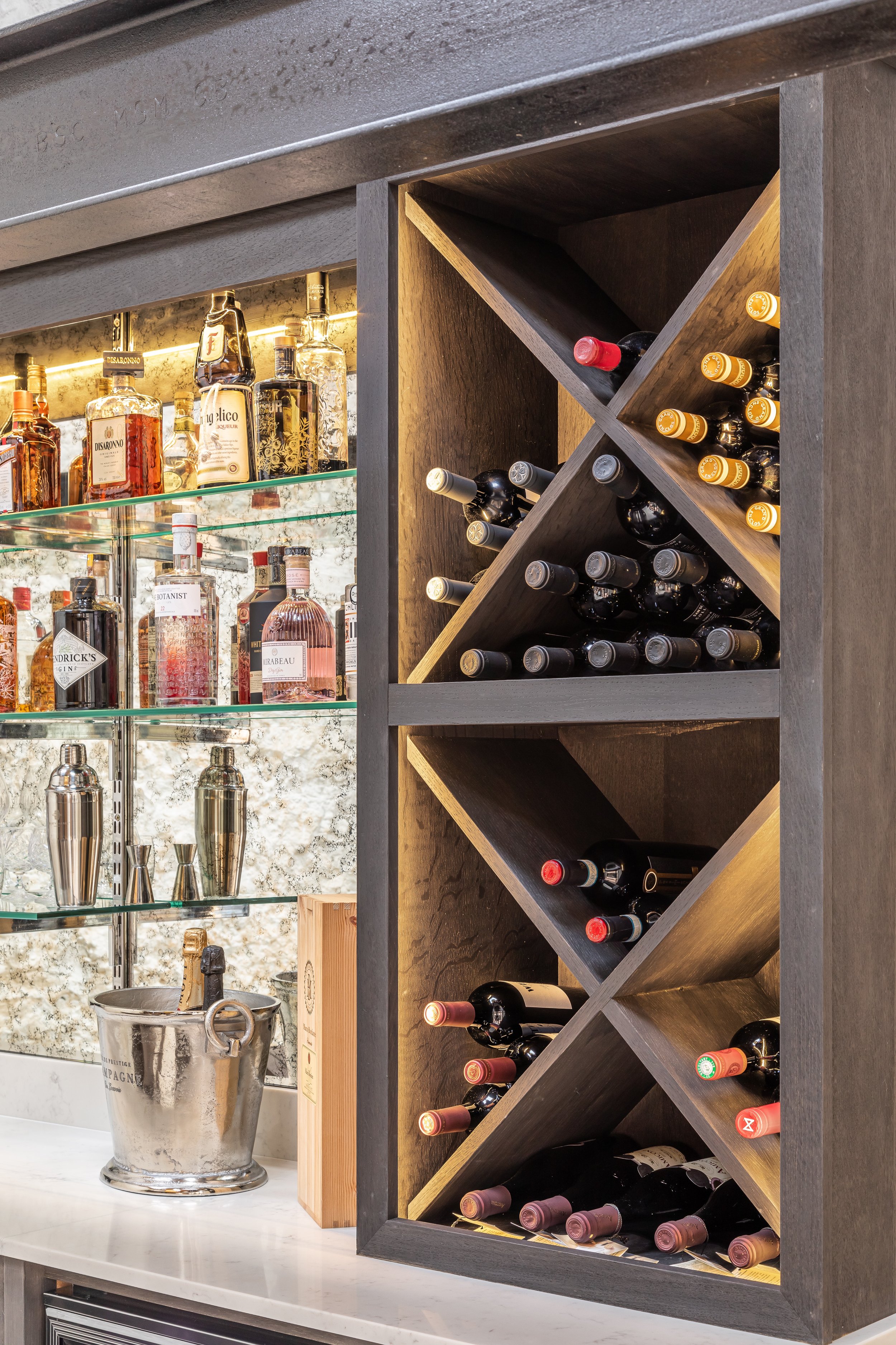 Home bar with liquor bottles, wine rack, and ice bucket on countertop.