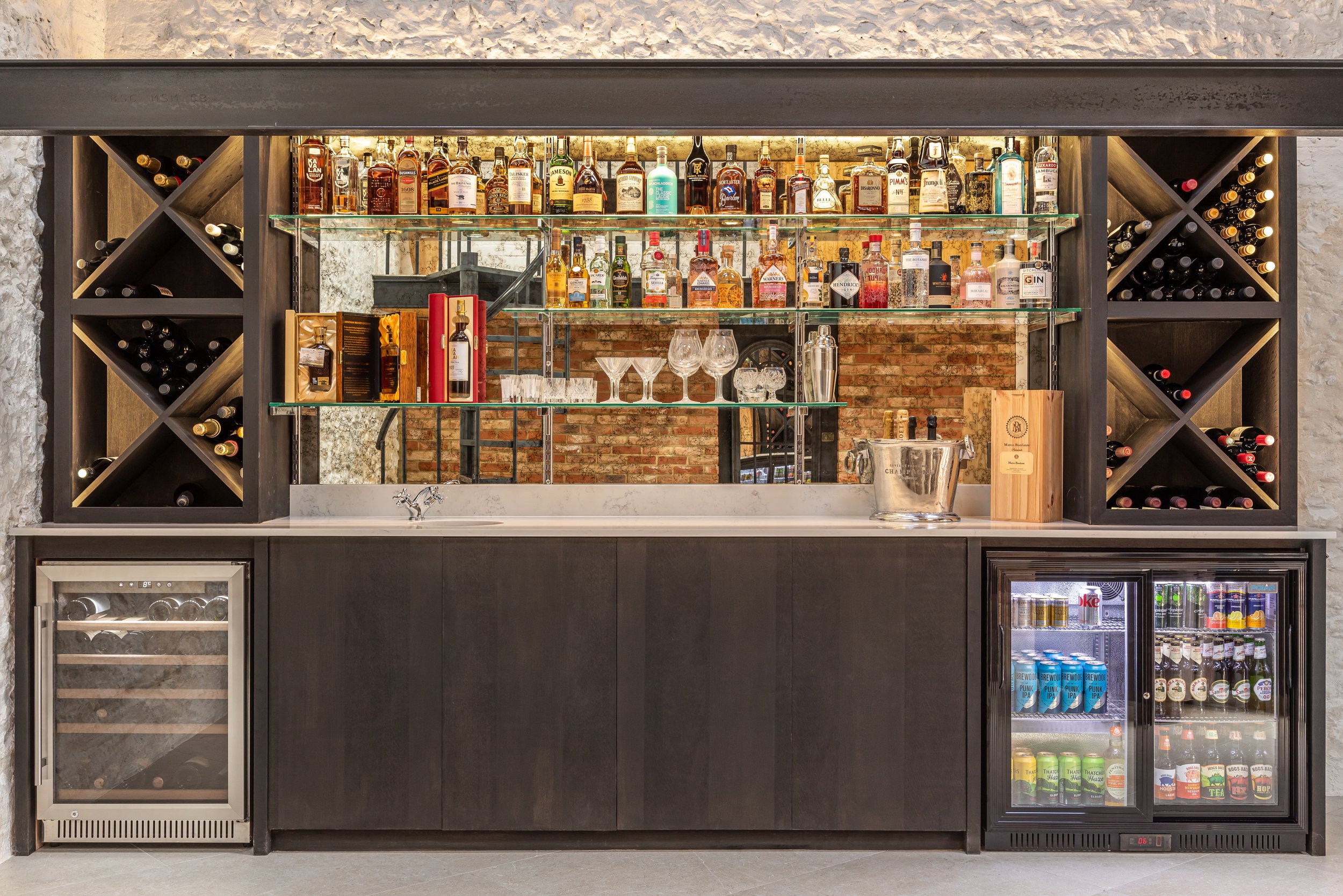 Home bar with liquor bottles, wine storage, glassware, and beverage fridge