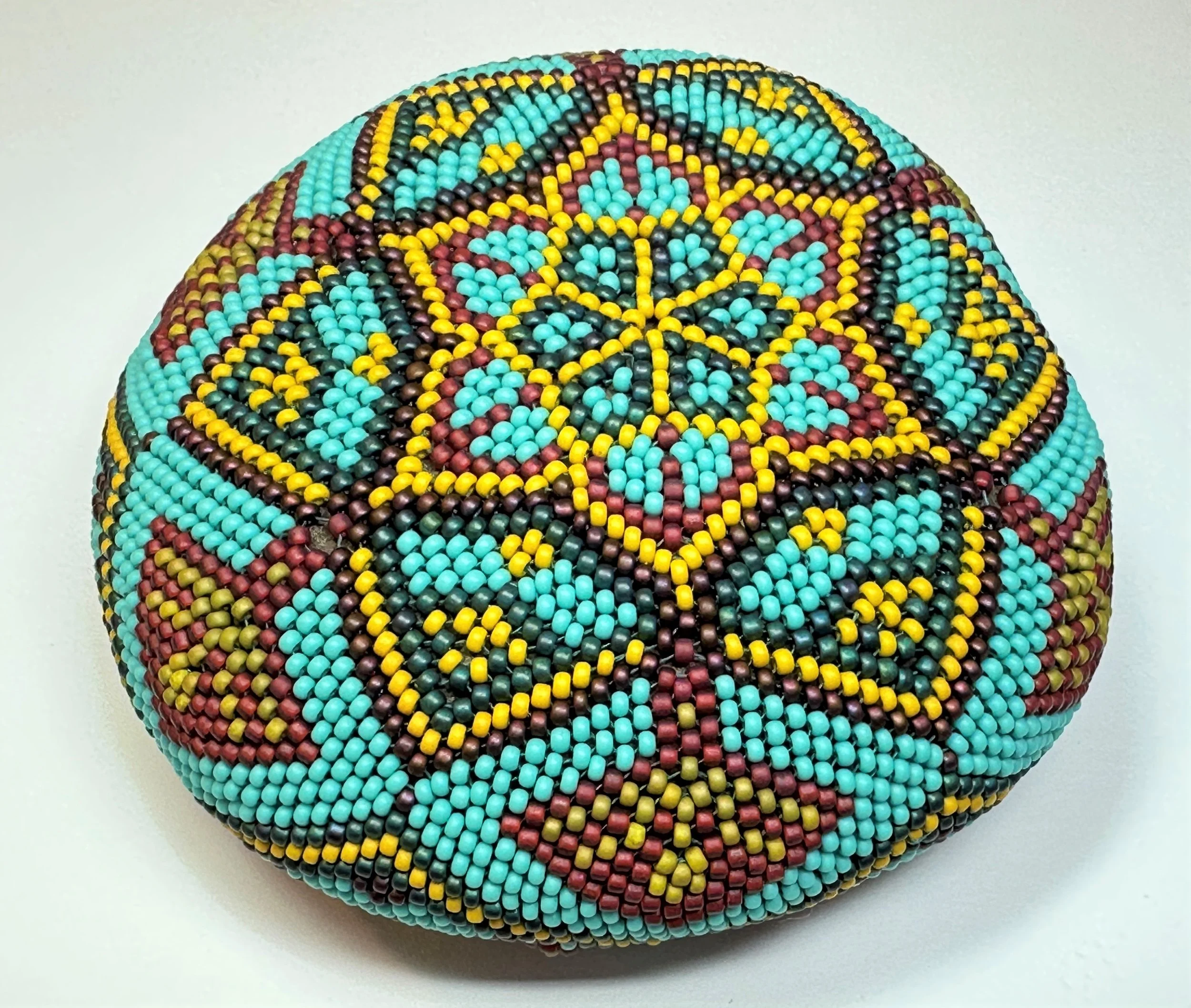This mandala stone is beaded in a design reminiscent of a cactus flower. It is beaded over a river rock and measures approximately 5-inches across. 