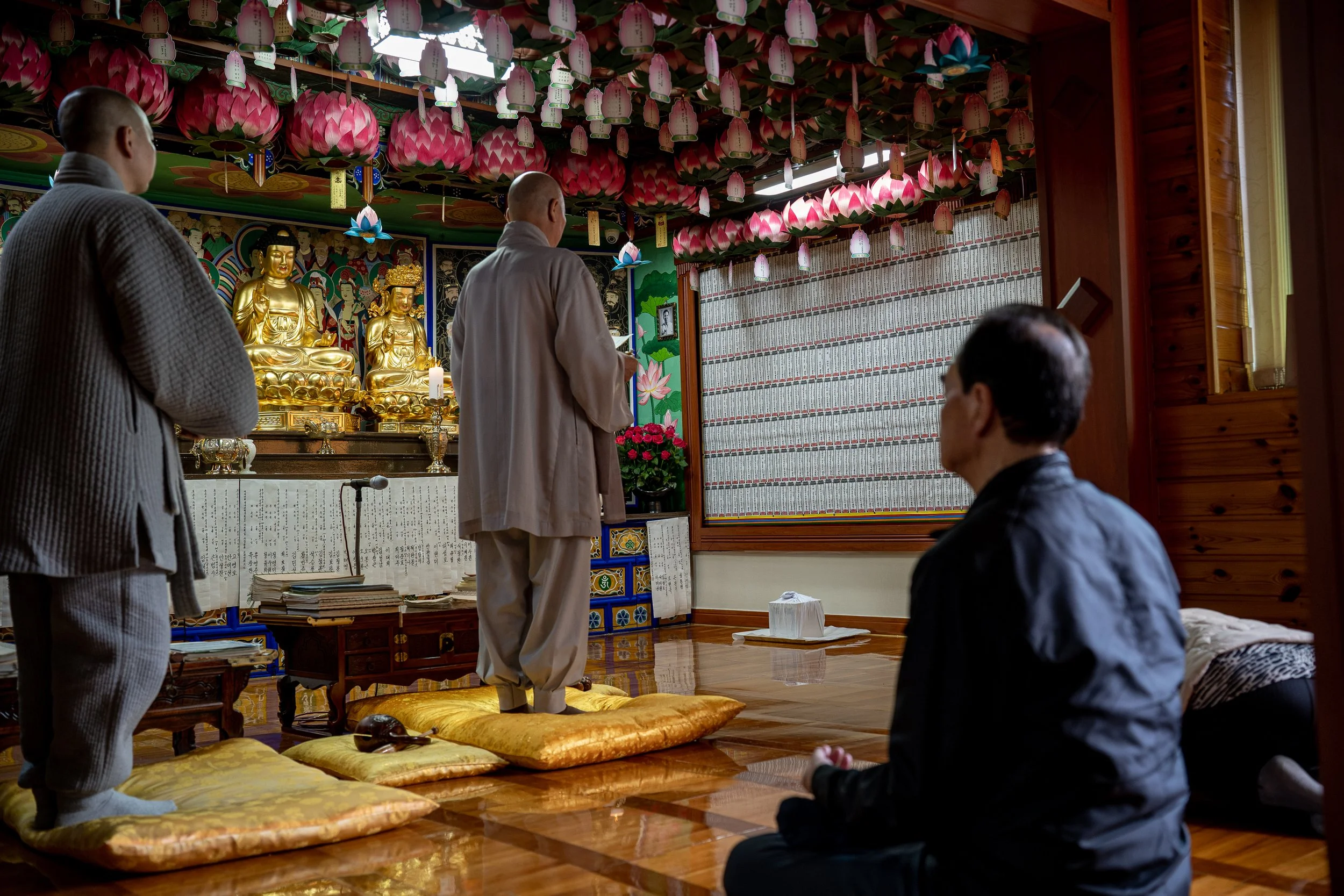 Lee Si-woo and Yoon Tae-yun pray at the temple in Busan where Lee Jong-wook's remains were taken to rest the night before the reinterring ceremony.