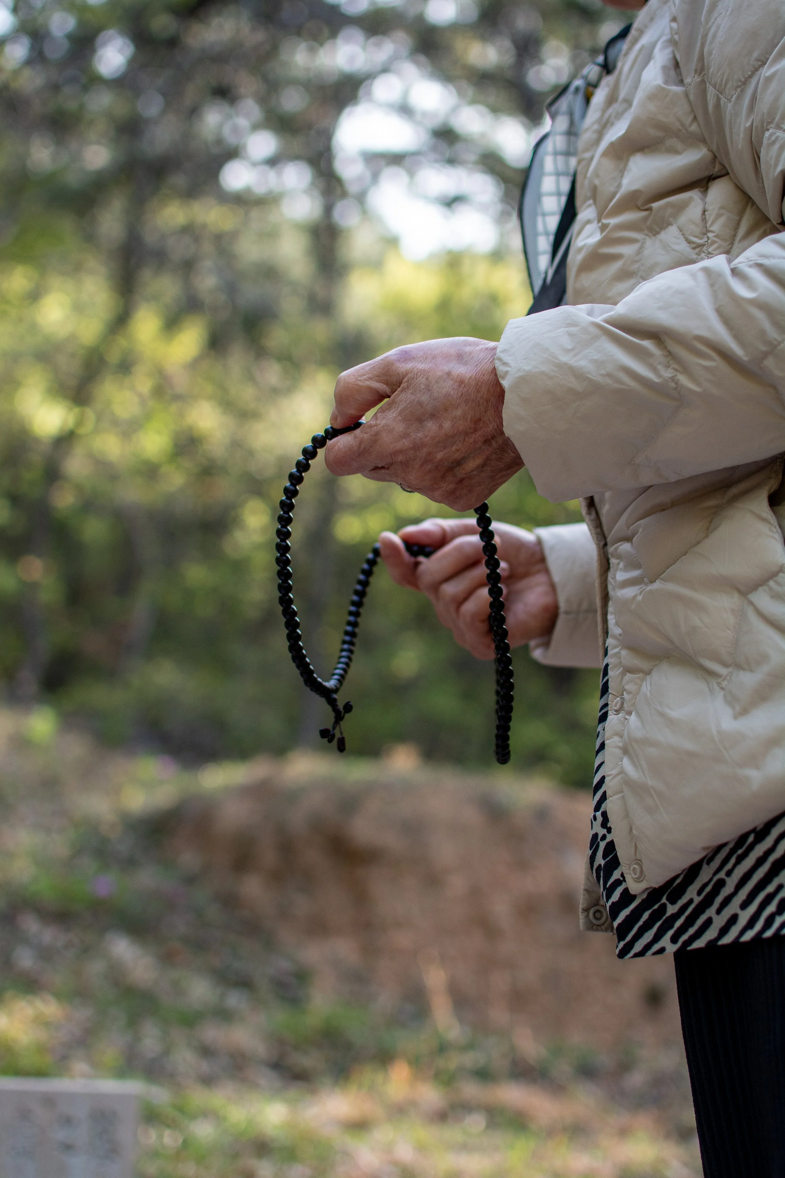Yoon Tae-yun holds prayer beads during the blessing prayers at the Lee family burial site in Busan.