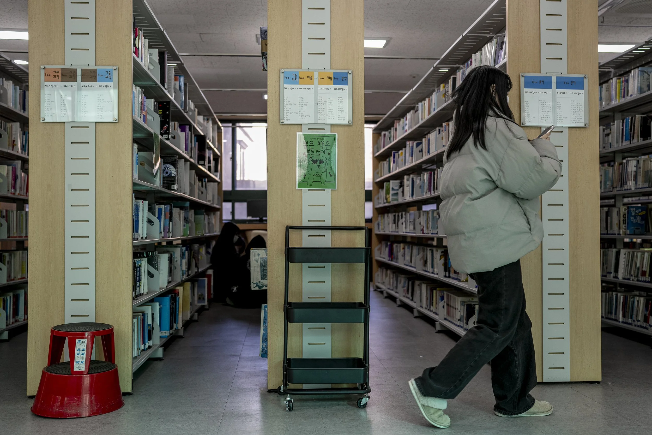 Students relax between the bookshelves in the library.