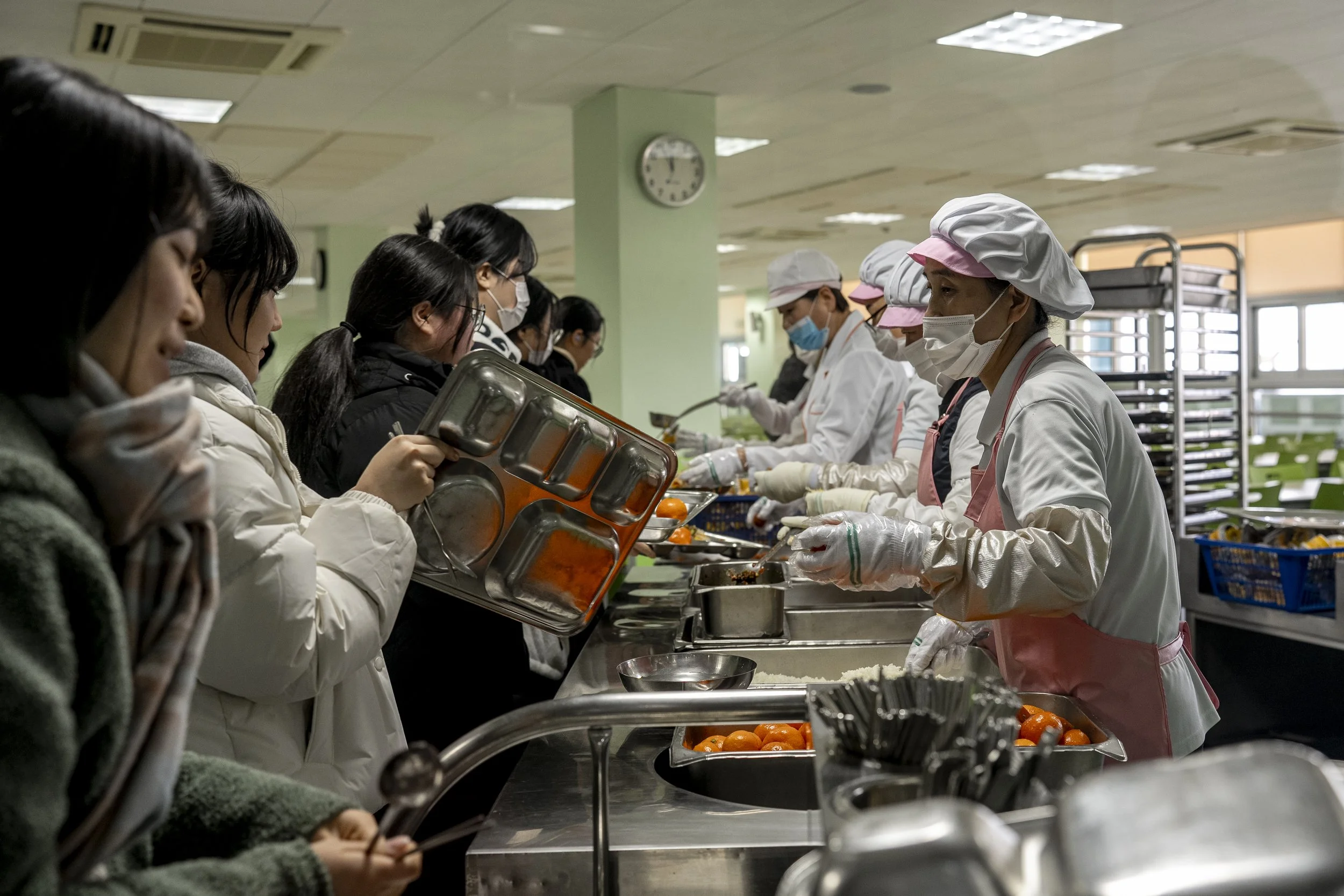 Workers serve lunch to the students at the cafeteria.