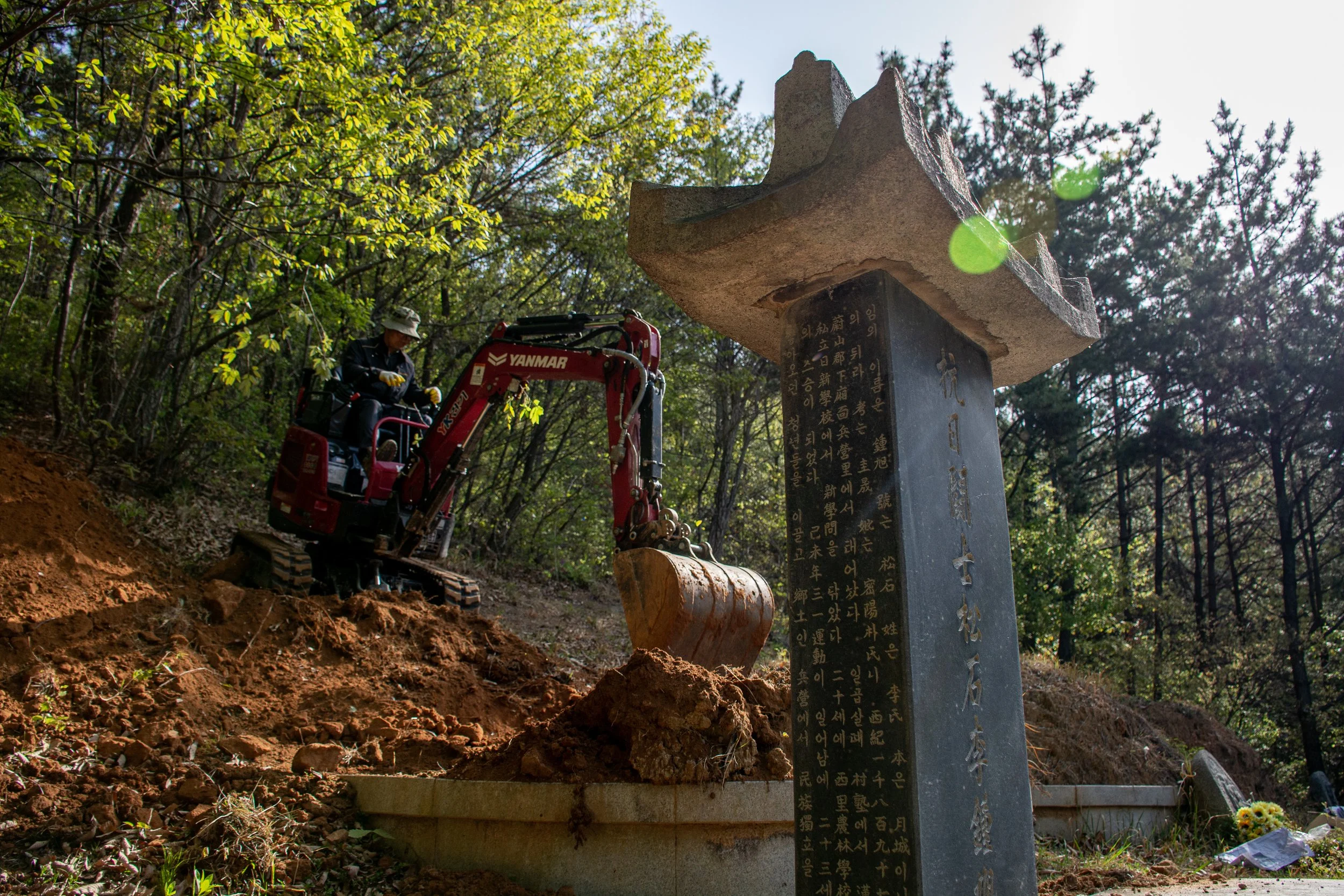 An excavator digs up the family memorial site in Busan.