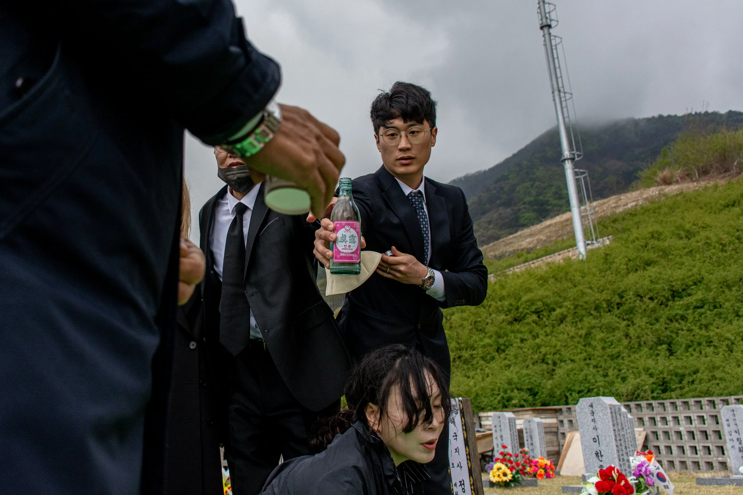Family members offer alcohol in honor of Lee Jong-wook during the reburial.