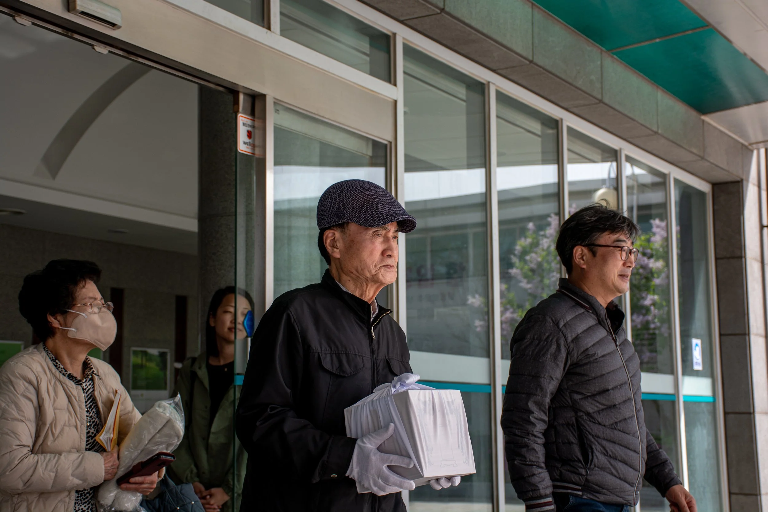 Lee Si-woo carries the remains of his father, Lee Jong-wook, from the crematorium to the temple in Busan.