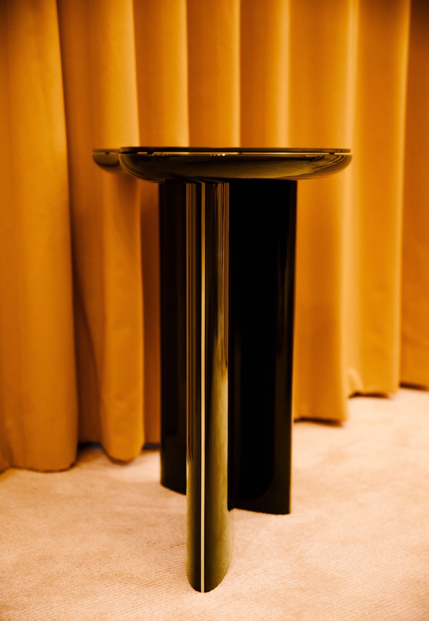 Modern black side table against yellow curtain