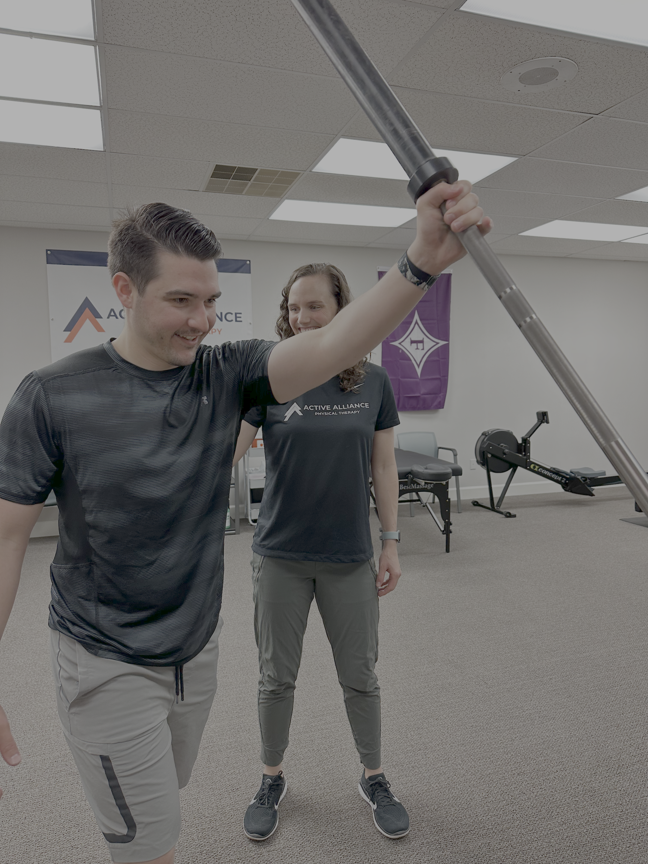 active man pressing barbell with physical therapist