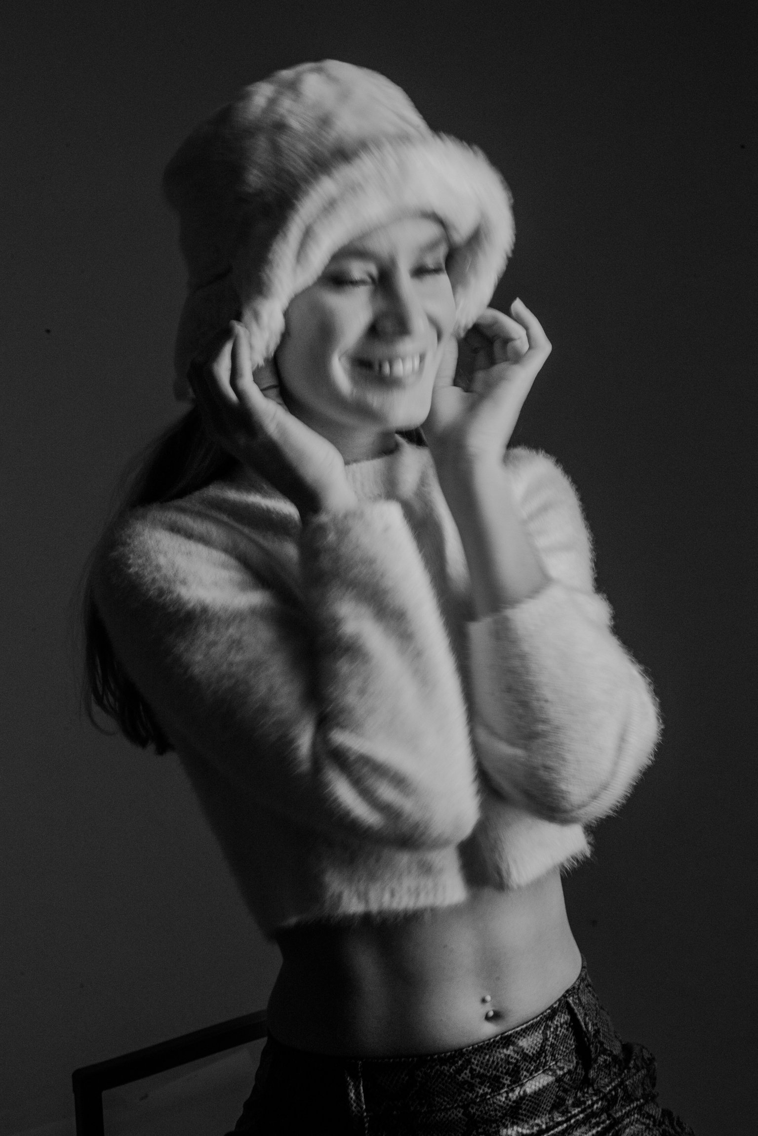 Mujer sonriendo con sombrero y suéter de pelo, retrato en blanco y negro.