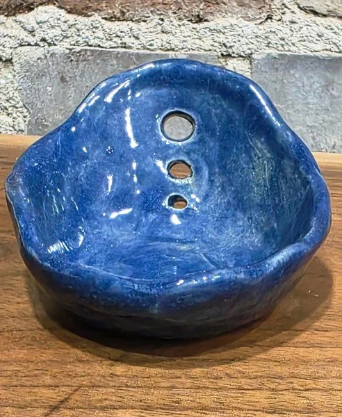 Example of the back view of a blue ceramic garden herb stripper with three holes.
