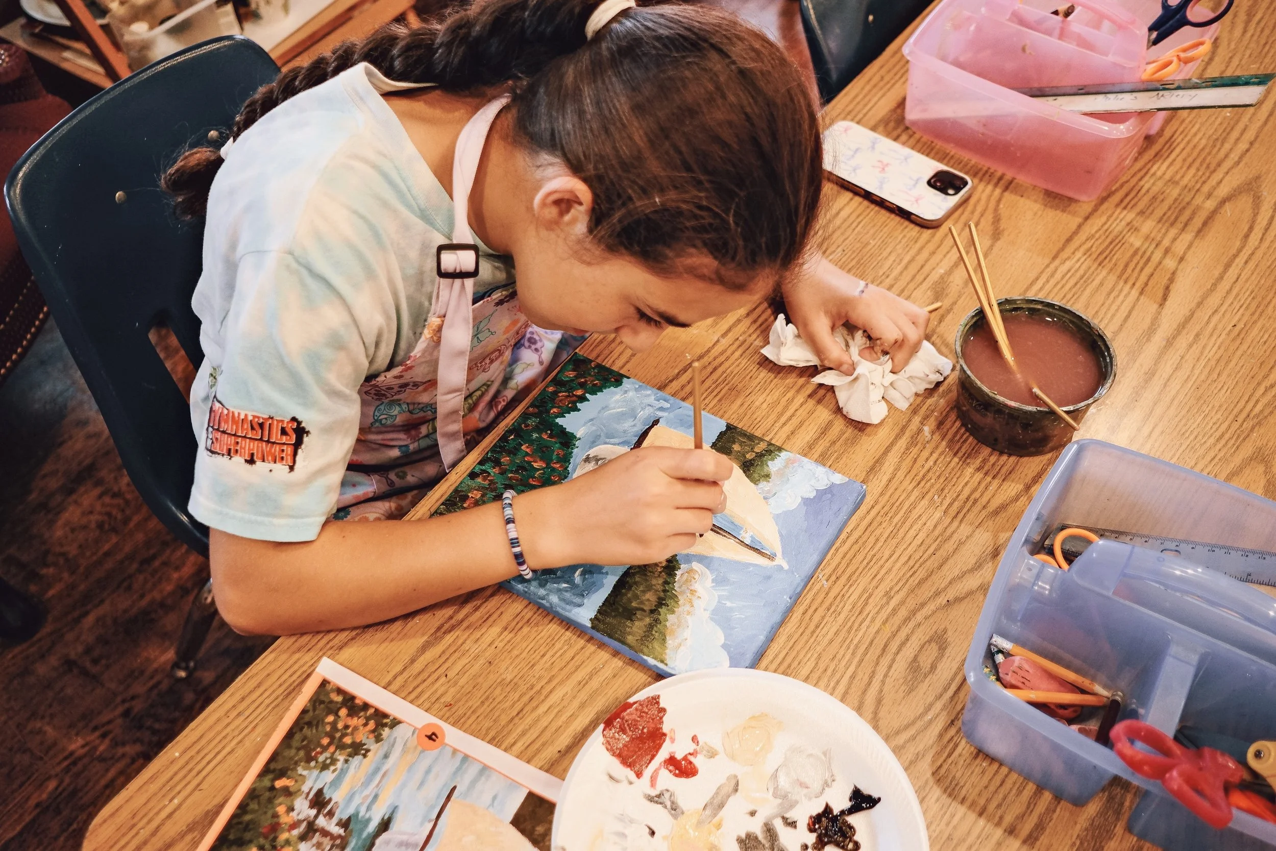 Young girl painting a boat in acrylic paint.