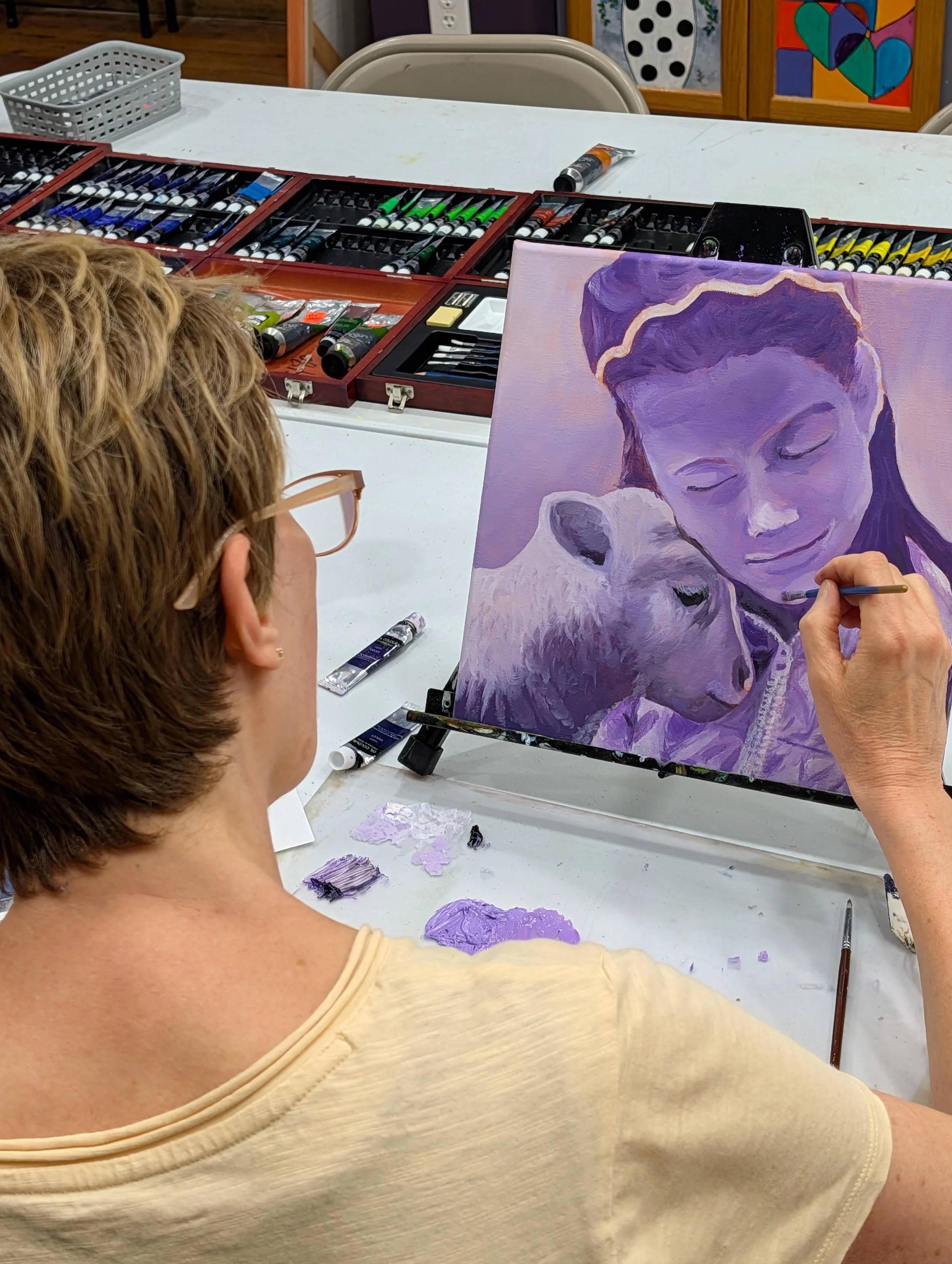 Adult female student painting a monochromatic portrait in class.