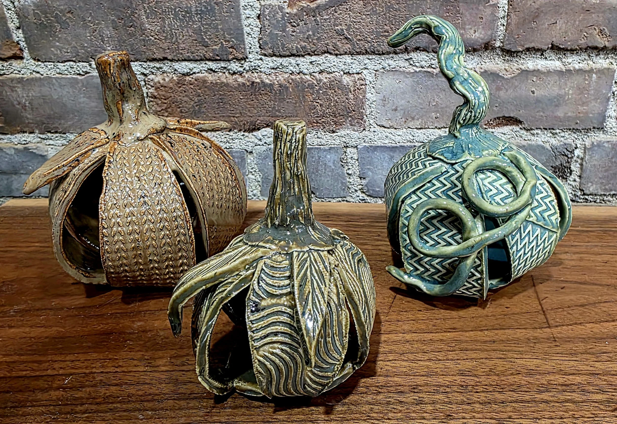 Three ceramic clay pumpkins glazed in green and brown glazes.