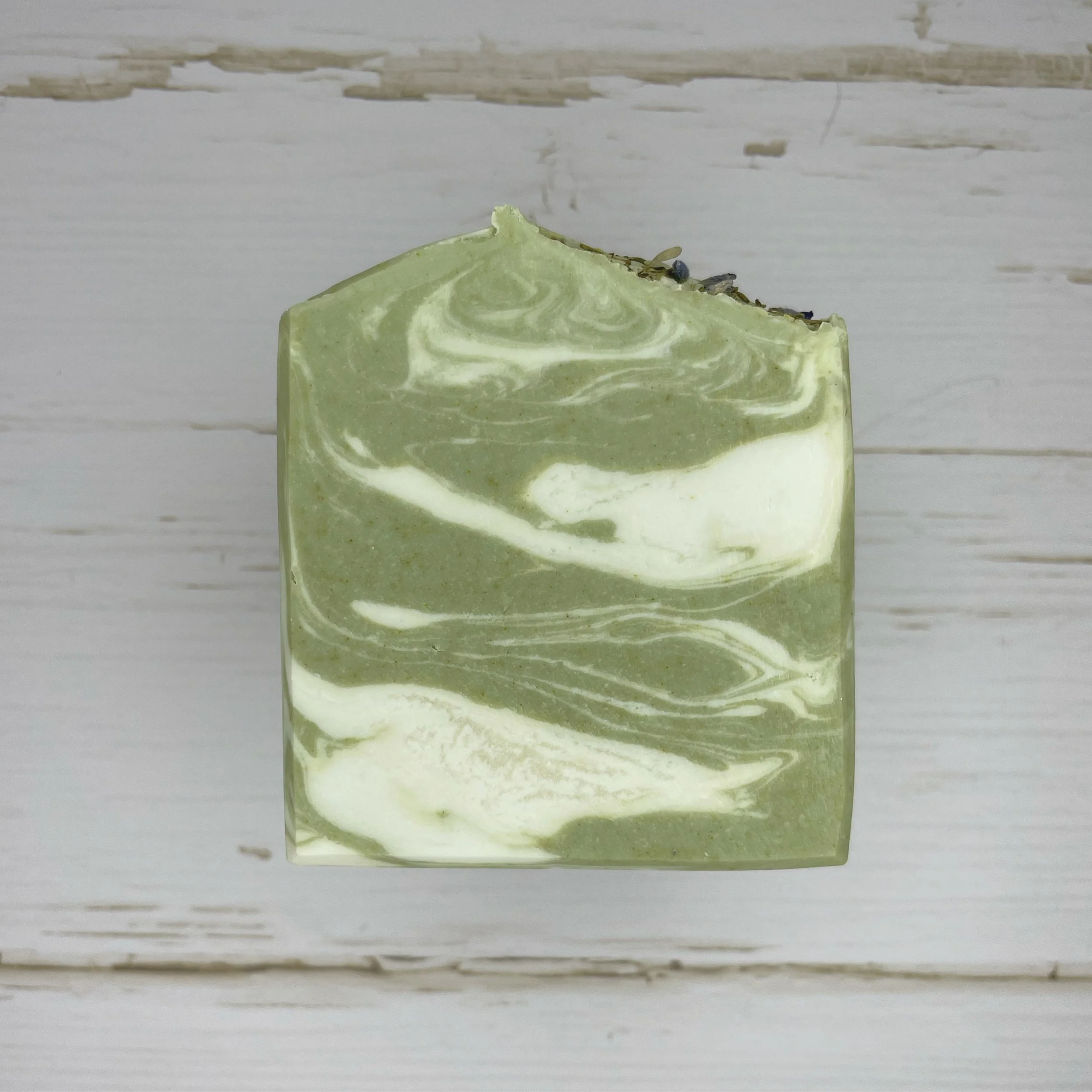An example of a handmade soap block with green and white swirls.