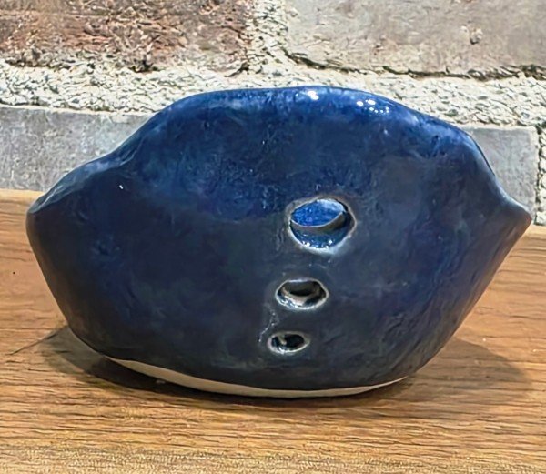 Example of the front view of a blue ceramic garden herb stripper with three holes.