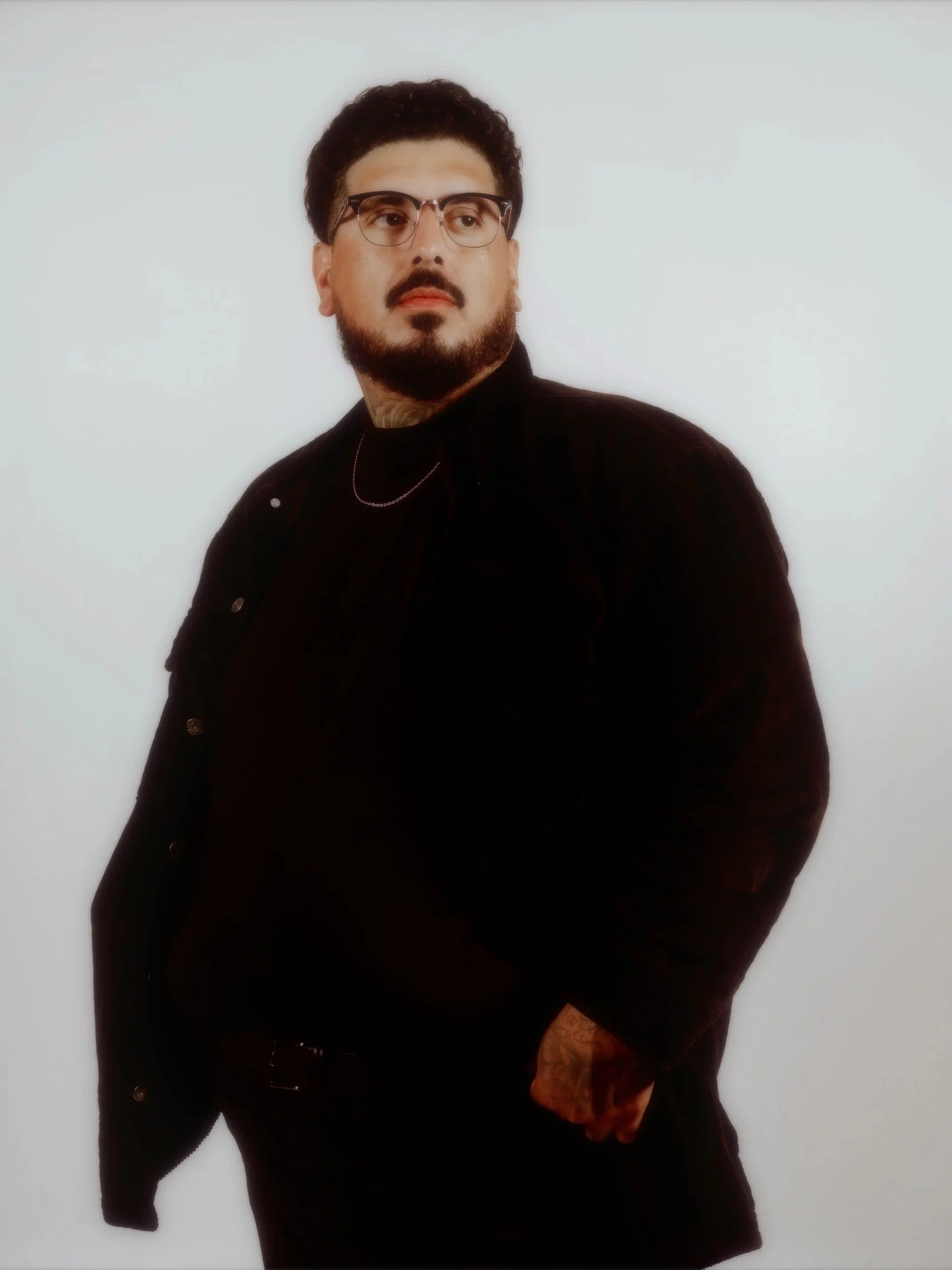 Portrait of photographer Eddie Lucero wearing a black coat against a white studio background.