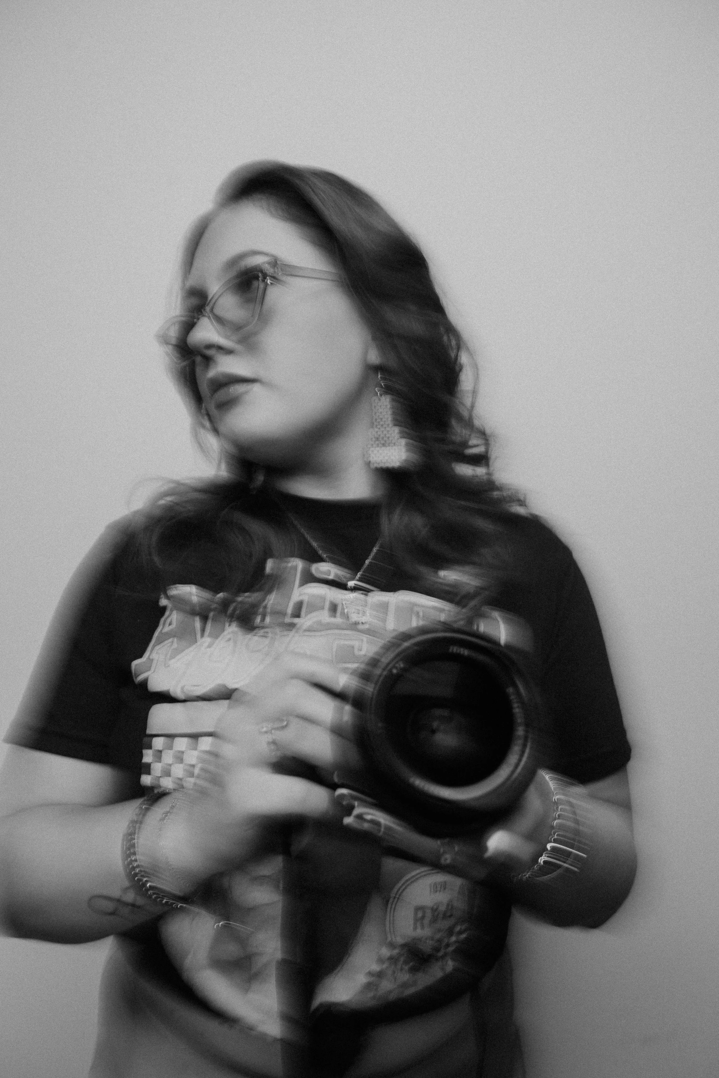 Black-and-white image of Alia holding a camera with intentional motion blur capturing movement.