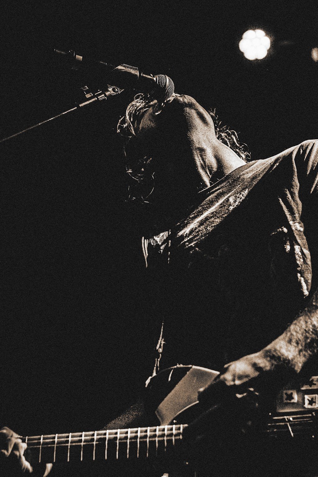 nick mateyunas (member arcy drive) singing into a microphone while playing an electric guitar in a dark setting.