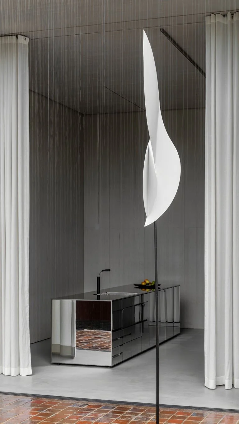 Minimalistisk interiør med tre træskamler ved en betonbar, dekorativ vase med grene, og hylder med keramiske skåle.