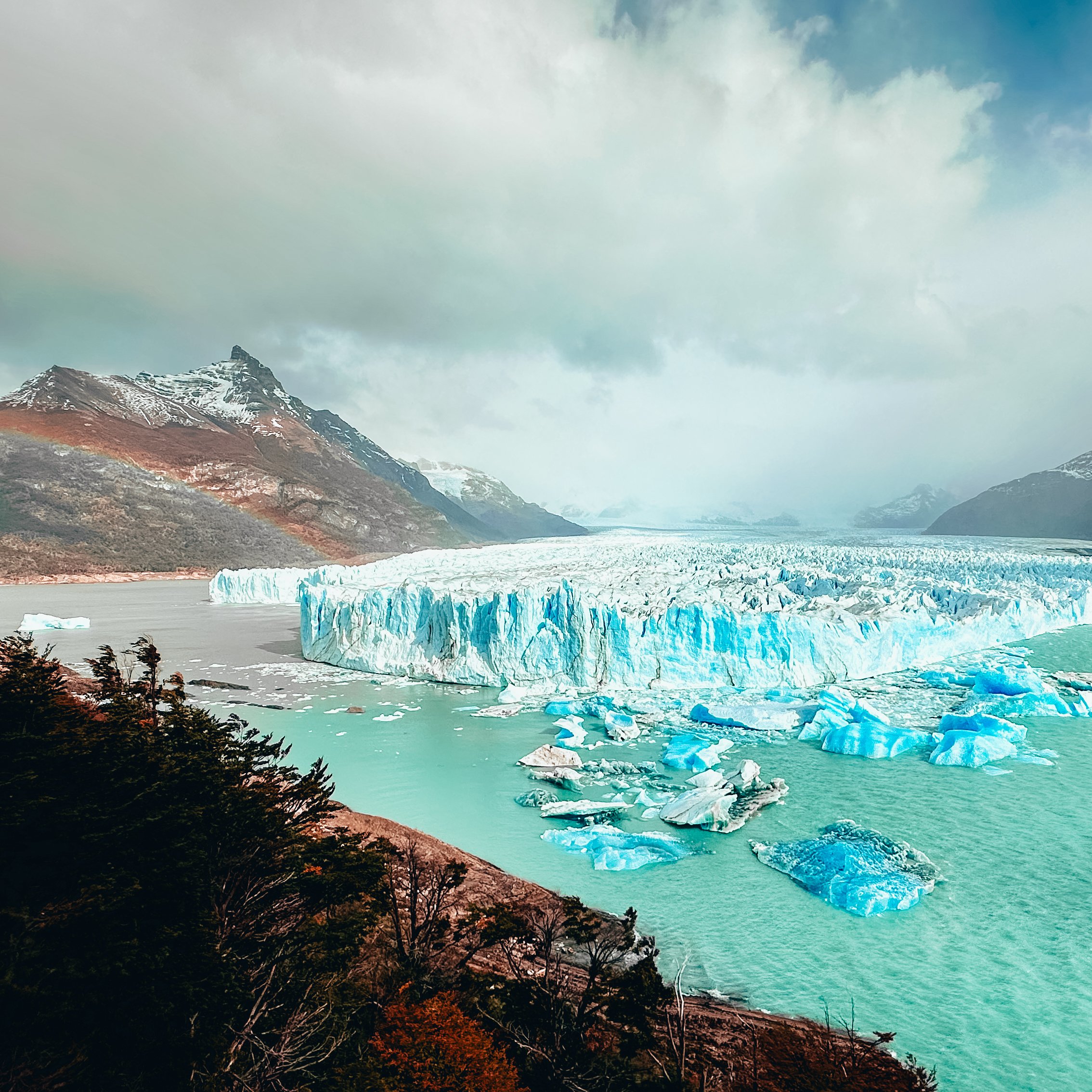 Perito Moreno Glacier in Patagonia, Argentina, with bright turquoise ice formations and floating icebergs in glacial lake under dramatic cloudy sky