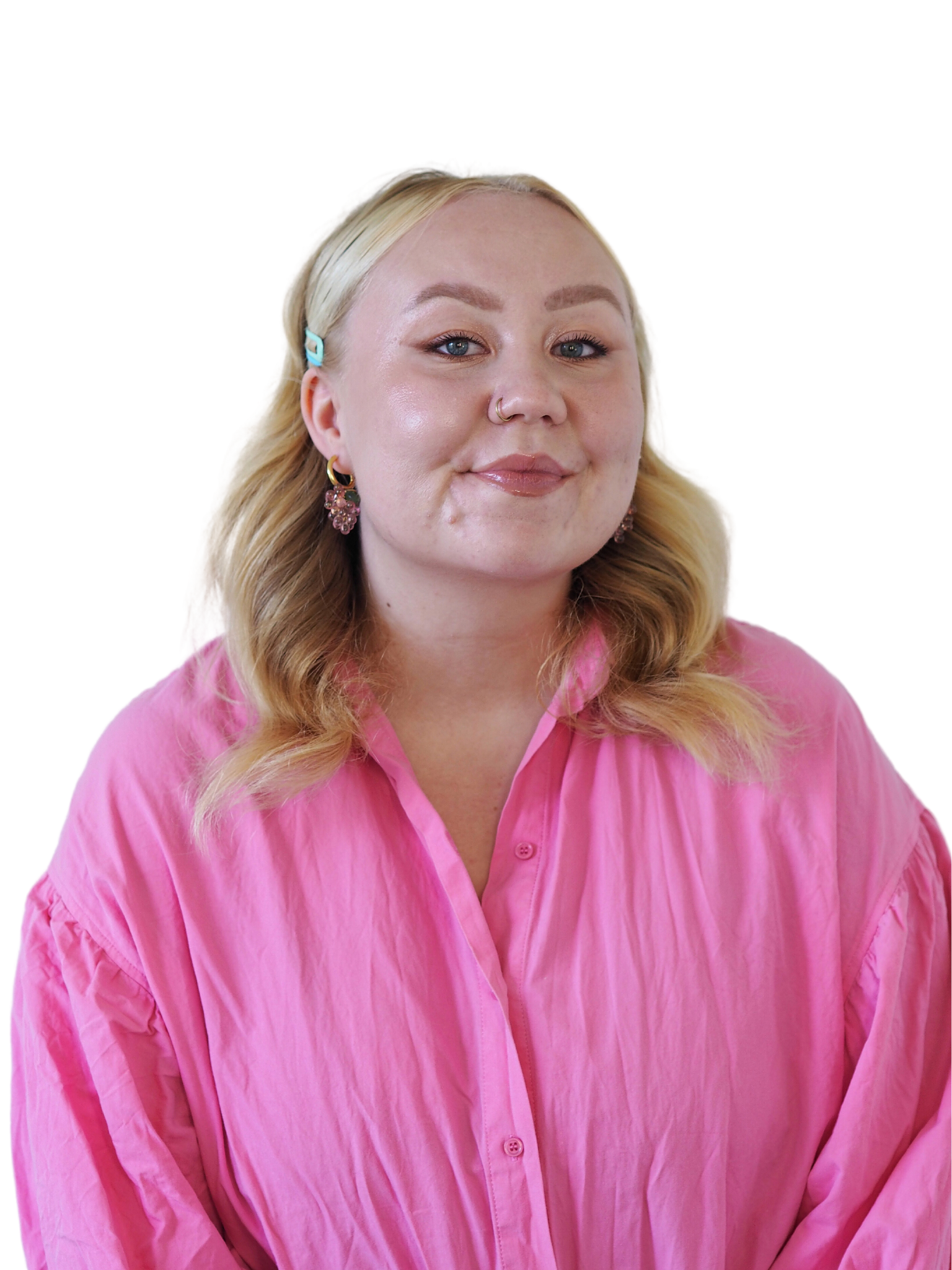 Nauraava nainen katsoo kameralle, hänellä on vaaleat hiukset, korvakorut ja nenän navigaattori, ja hän on pukeutunut pinkkiin puseroon.