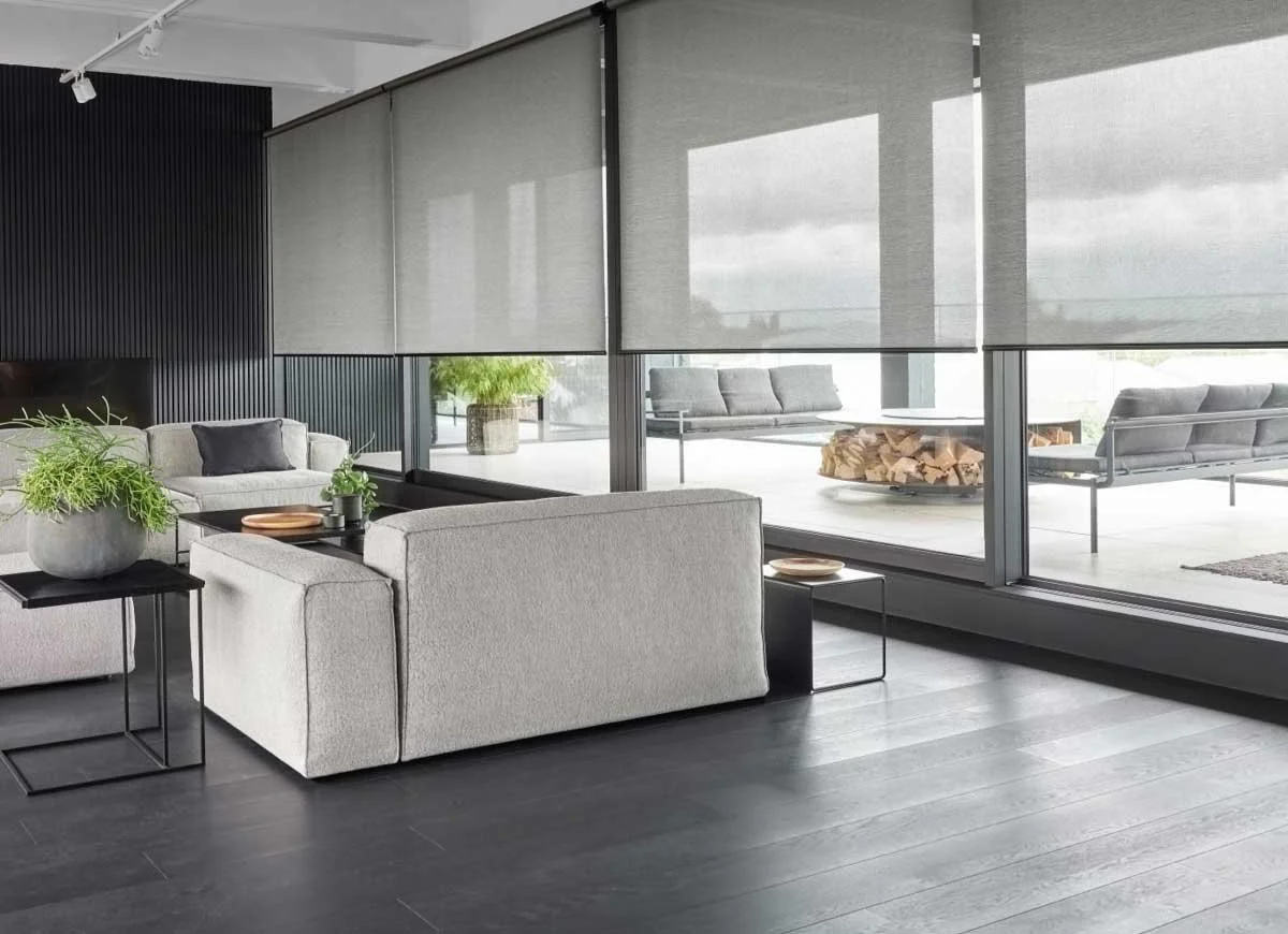 Modern living room with wide windows fitted with motorized roller shades