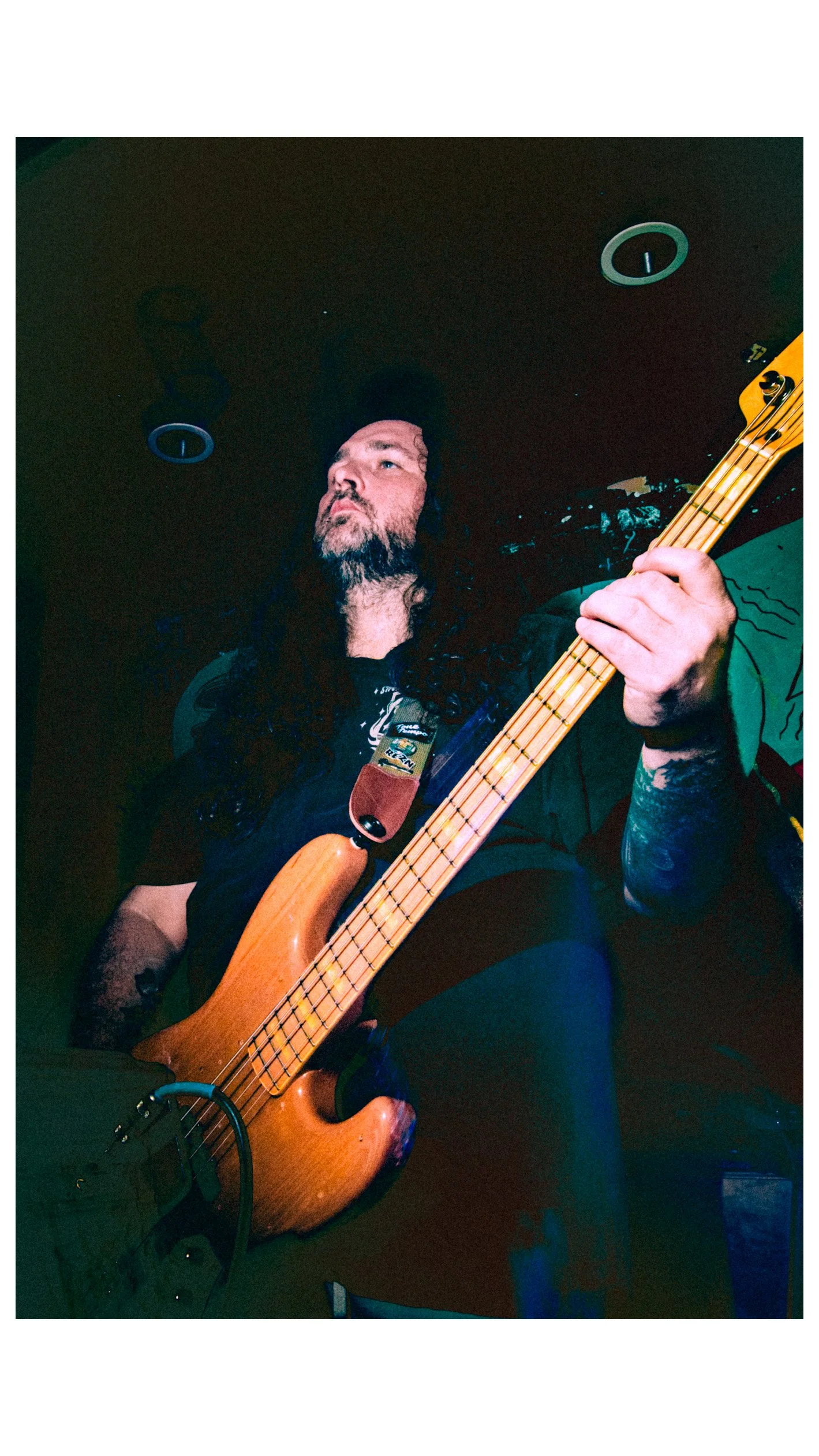 Tysonious Mink, bassist for the band Liquid Pennies playing a bass guitar on stage.