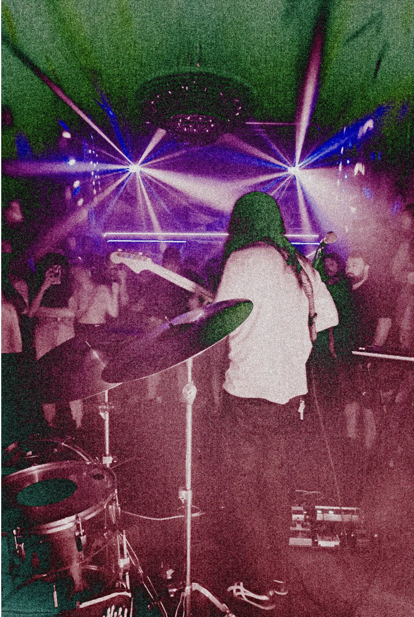 Chas Binns of the band Liquid Pennies from Tampa Bay Florida playing a Fender Jazzmaster guitar at a live concert with bright colorful laser lights and dancing crowd in the background. with purple and blue laser lights in the background.