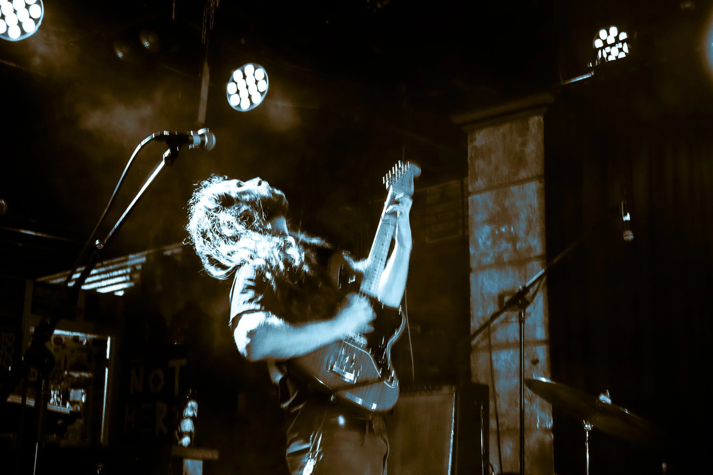 Rock band Liquid Pennies frontman/guitarist Chas BInnsplaying an electric guitar on stage during a live music performance, with stage lights overhead and fog at The Crowbar in Ybor City Florida during a show with The Bright LIght Social Hour.
