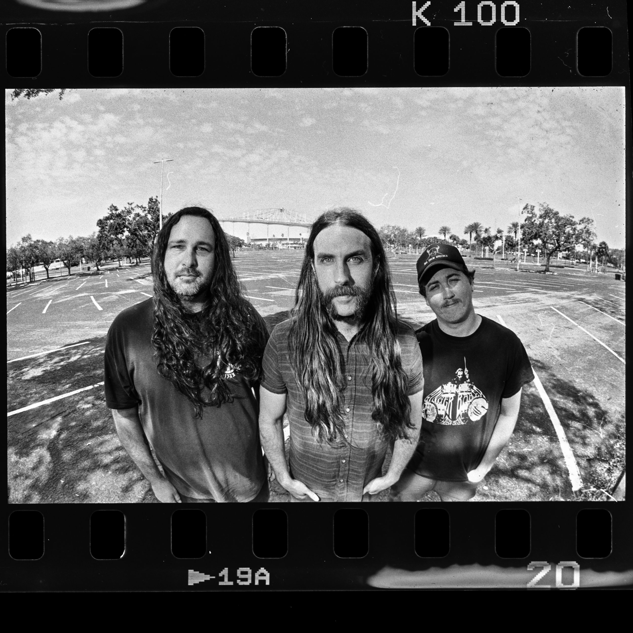Liquid Pennies official press photo in 2025 in front of the dilapidated Tropicana Field in Saint Petersburg Florida. The photo is taken on film and is in black and white. Photo appears in the vinyl insert of Liquid Pennies' fourth album Fore.