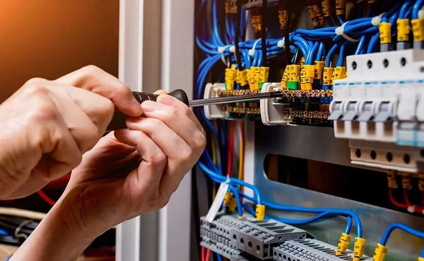 Person working on electrical wiring inside a control panel or electrical cabinet