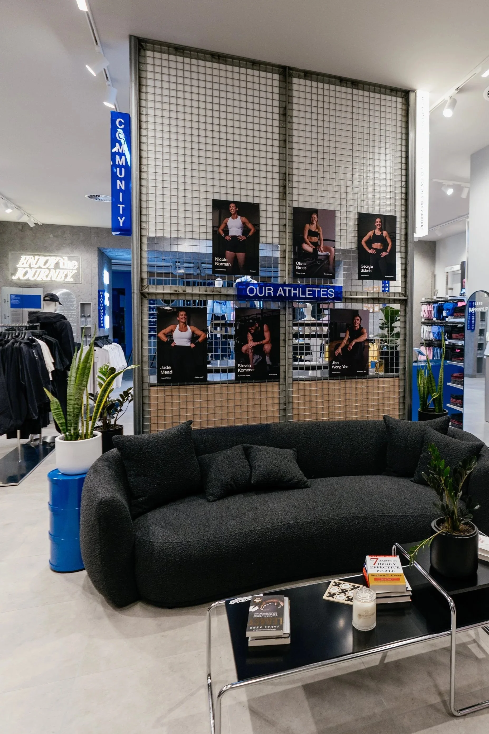 LSKD Karrinyup community lounge with a dark sofa, blue fixtures and Our Athletes display.