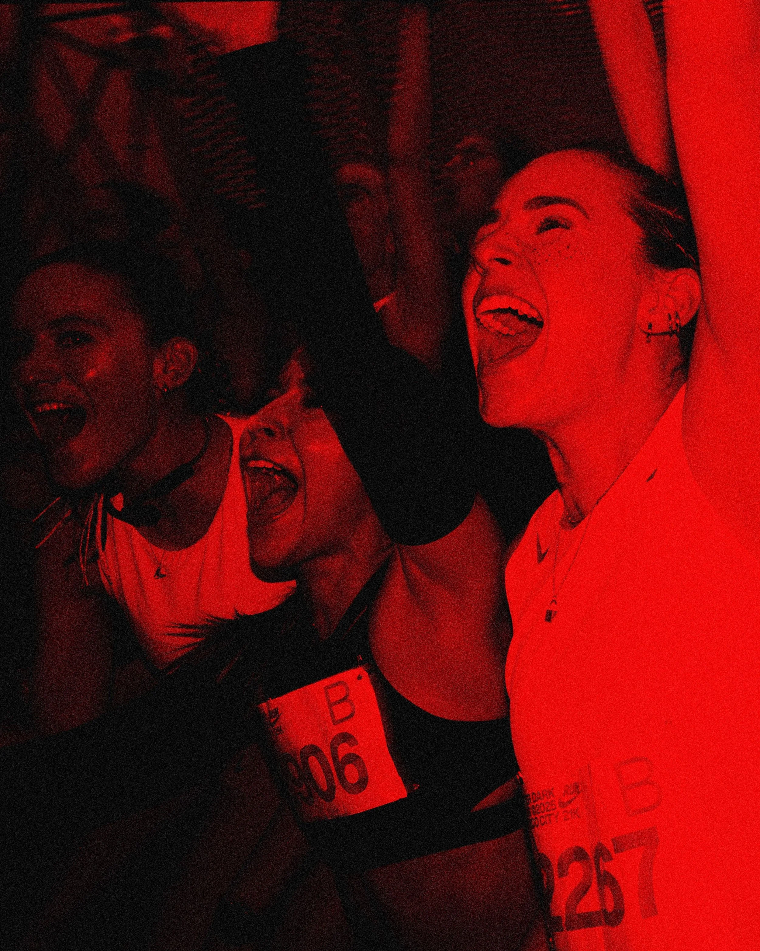 Two participants celebrating under red lighting in Nike After Dark Tour series photography.