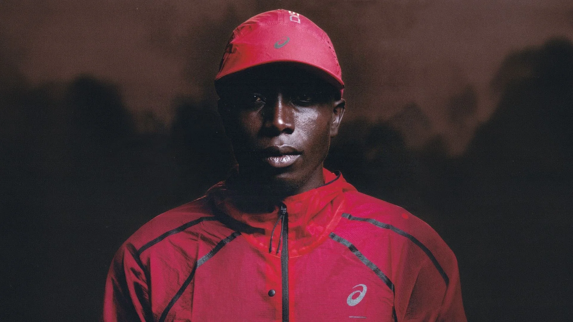 Runner wearing a red cap and jacket in the ASICS × Distance Iten campaign.