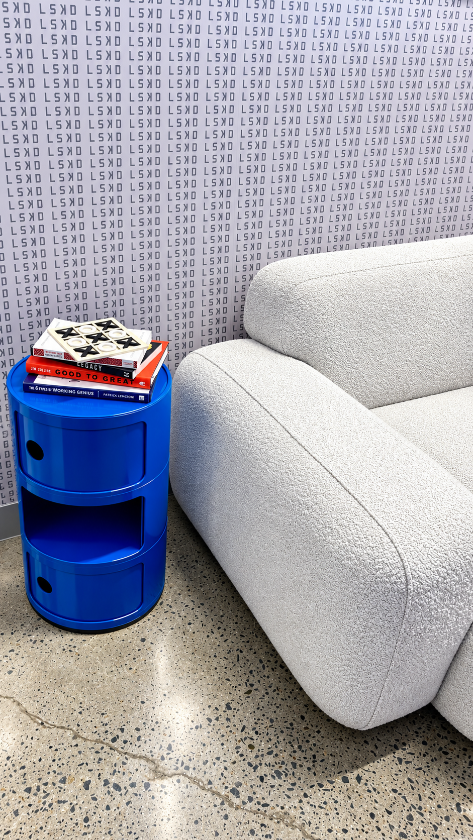 White textured seating beside a cobalt blue table and a stack of books.