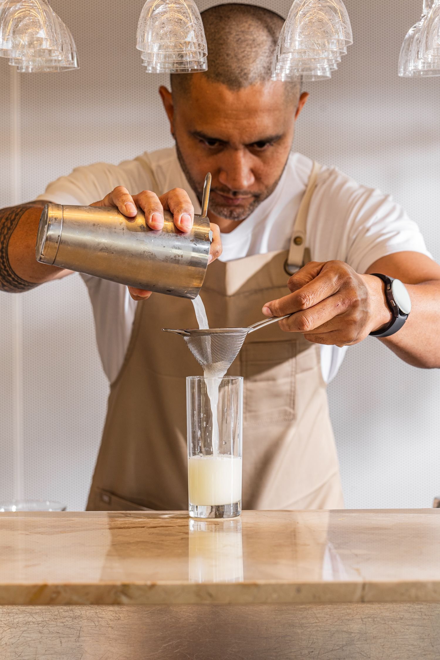 Bartender straining a cocktail over a glass