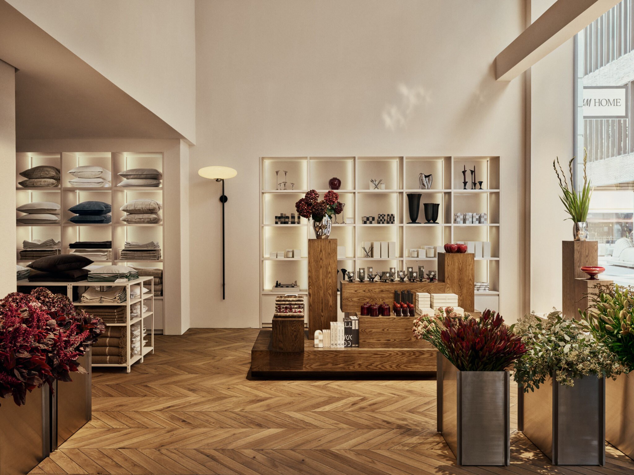 Warm timber displays, pale shelves and flowers inside H&M Home’s renovated Stockholm flagship.