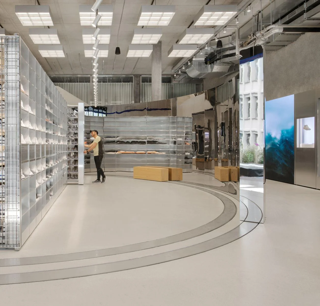 Curved mirrored display walls, shoe shelving and timber benches inside the On Labs flagship in Zurich.