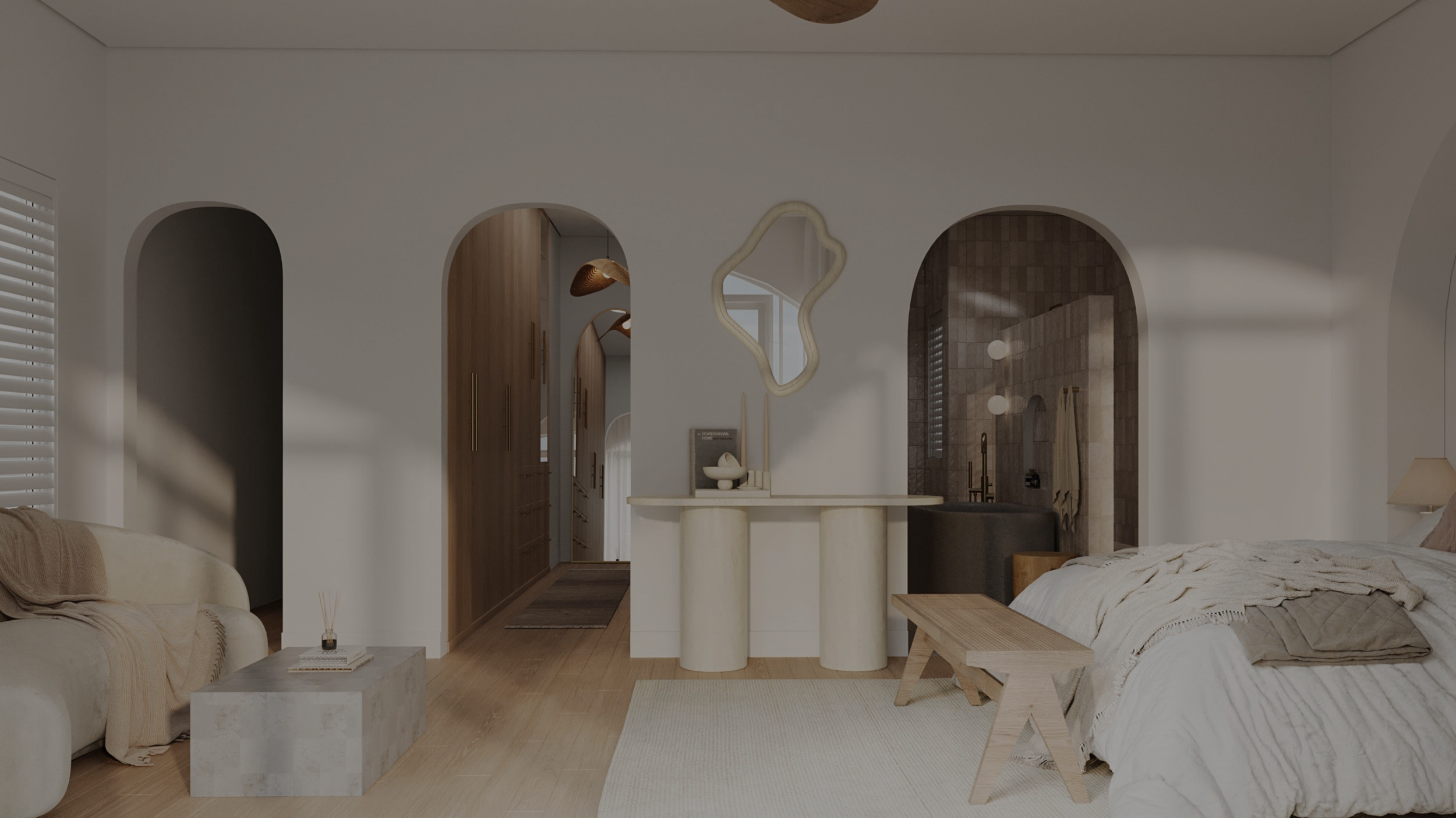 A modern bedroom with a white bed, wooden bench, beige sofa, decorative mirror, and an open doorway leading to a bathroom with tiled walls.