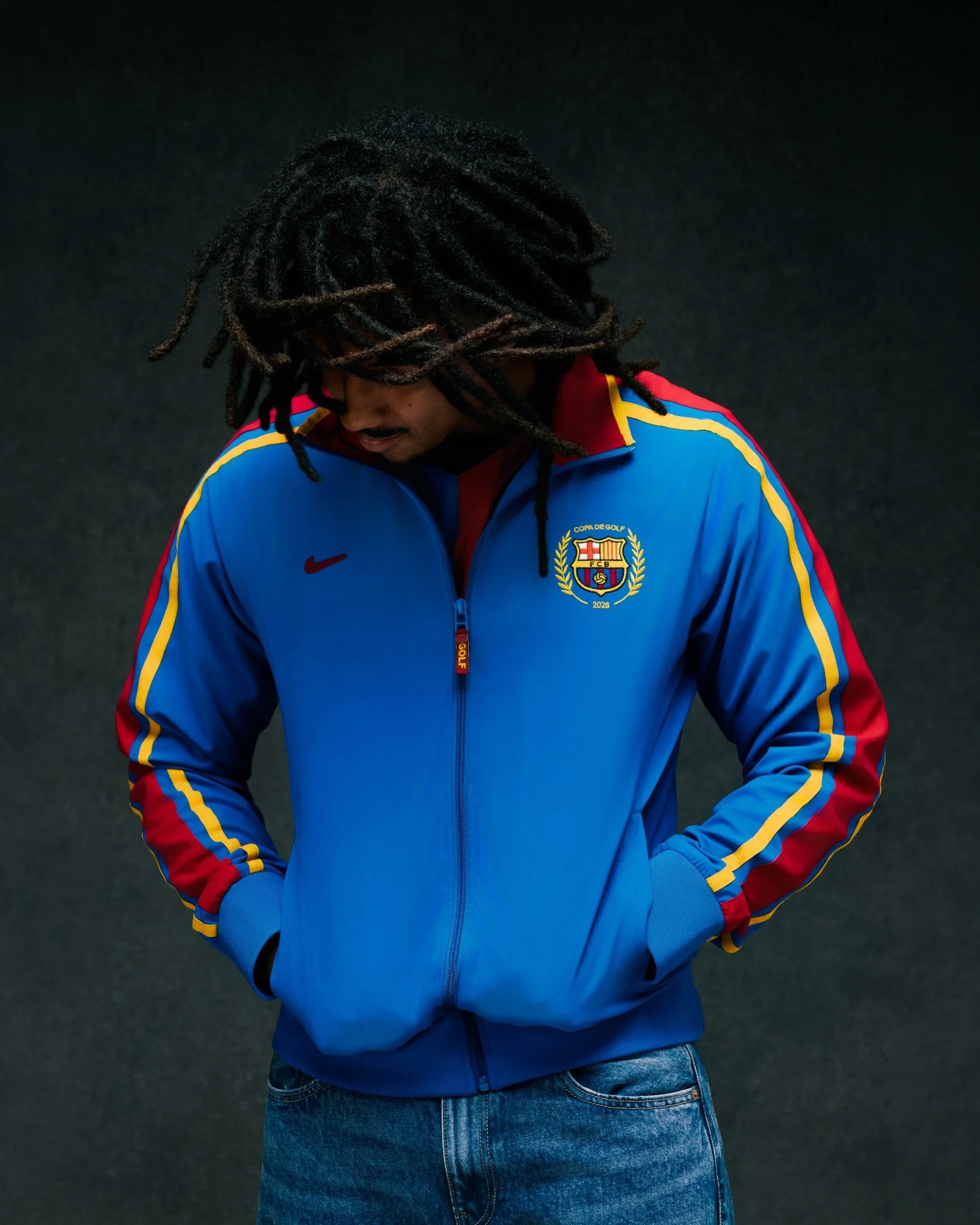 Jules Kounde wearing a blue FC Barcelona × GOLF WANG track jacket with red and yellow sleeve stripes.