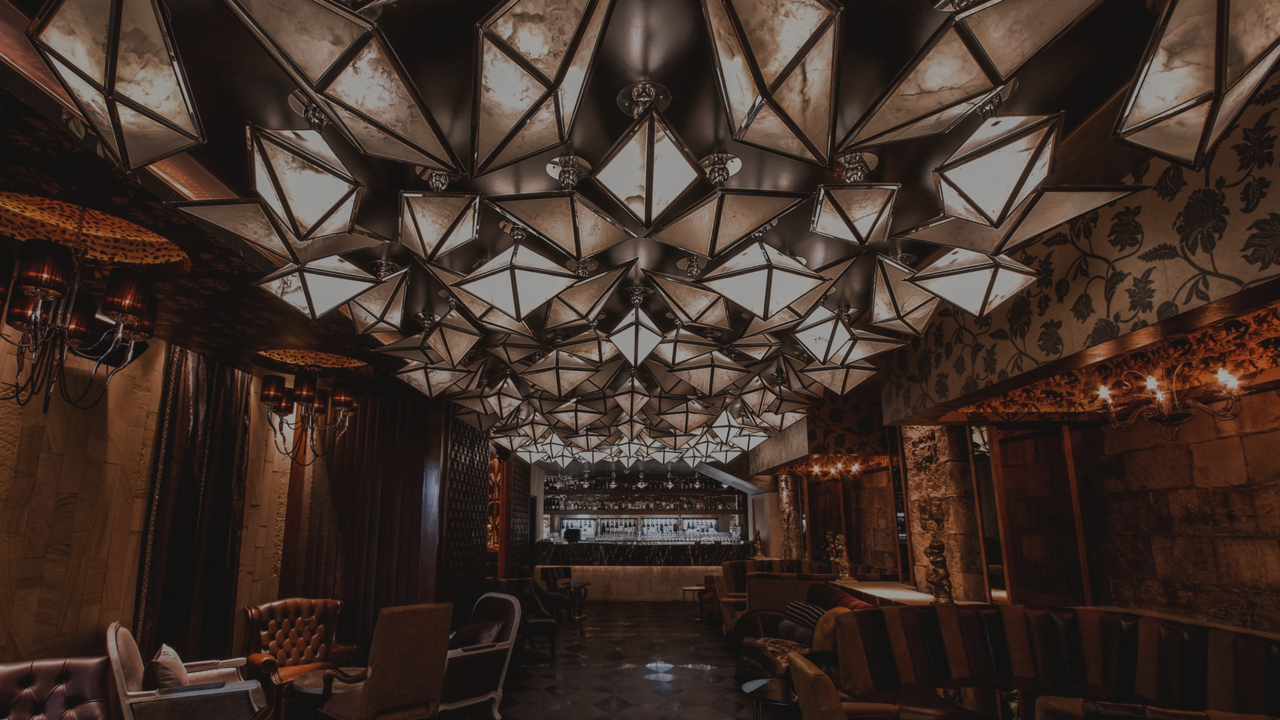 Elegant lounge with geometric ceiling lights and vintage furniture.