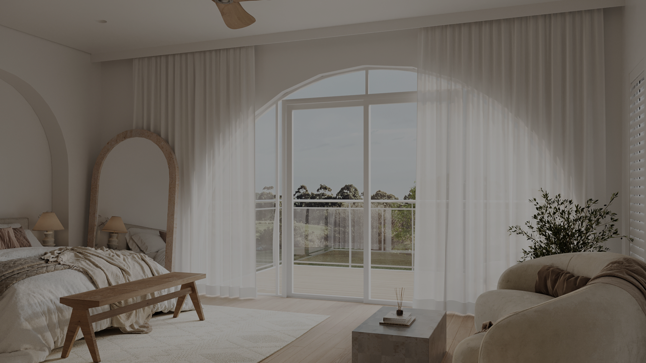 Bright bedroom with large sliding glass door leading to balcony, white curtains, bed with beige and brown bedding, mirror, small bench, and sofa with dark throw blanket.