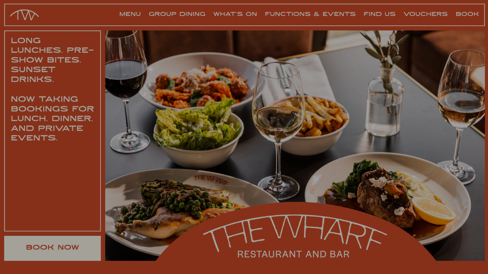 A restaurant table set with assorted dishes, including a bowl of pasta, a bowl of salad, and a plate with meat and vegetables, along with glasses of red and white wine, a vase with greenery, and a water glass. The restaurant's menu and booking inform