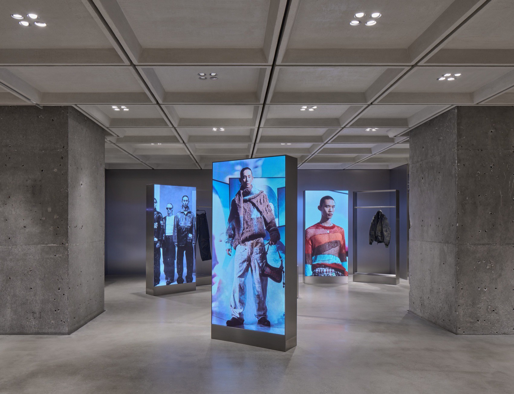 Freestanding digital displays showing fashion imagery inside the concrete interior of Zara’s Nanjing flagship.
