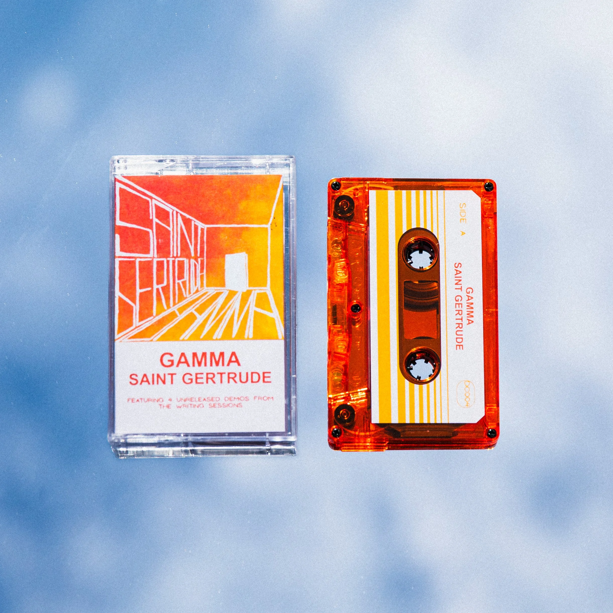 A cassette tape and its case labeled 'GAMMA SAINT GERTRUDE' with orange and yellow artwork, placed on a light blue surface.